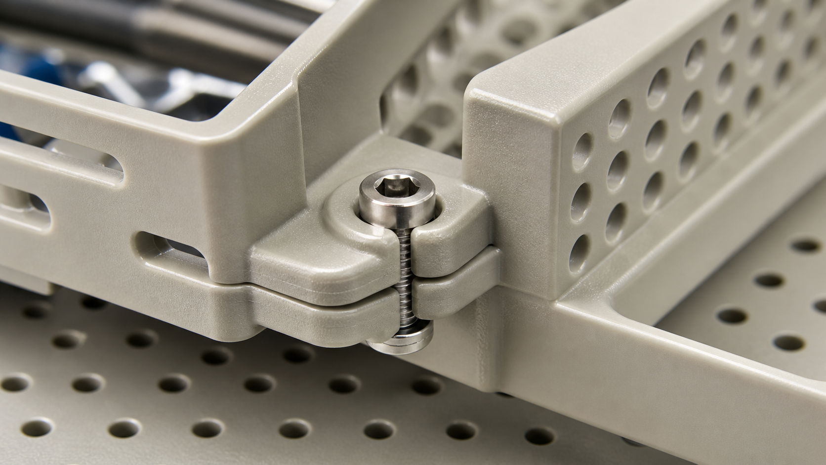 Examining how material substitution affects mechanical fasteners and joints. Close-up of a metal fastener joining two high-performance polymer components inside a medical sterilization tray.